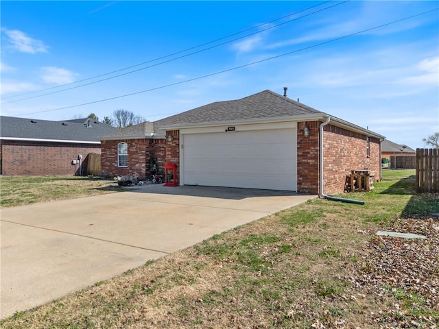 view of side of property featuring fence, a yard, concrete driveway, a garage, and brick siding