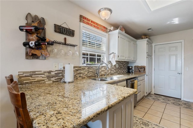 kitchen featuring tasteful backsplash, visible vents, light stone countertops, light tile patterned floors, and a sink