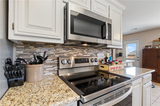 kitchen featuring visible vents, tasteful backsplash, stainless steel appliances, white cabinets, and light stone countertops