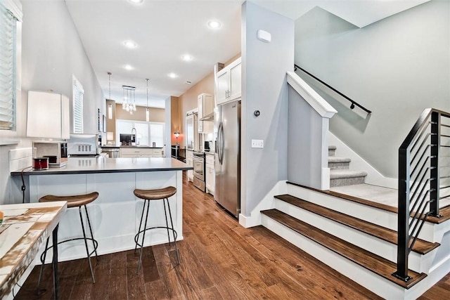 kitchen featuring dark wood-style floors, a peninsula, stainless steel fridge with ice dispenser, a sink, and white cabinetry