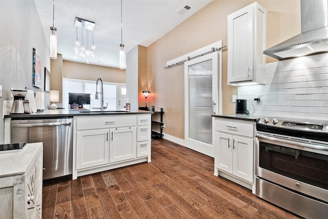 kitchen featuring visible vents, a sink, dark countertops, stainless steel appliances, and wall chimney exhaust hood