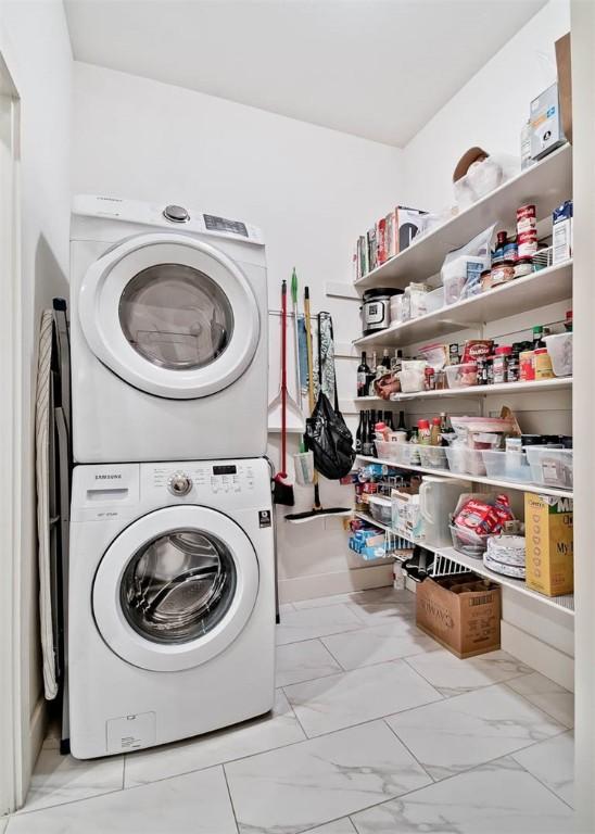 laundry room with marble finish floor, stacked washer / dryer, and laundry area