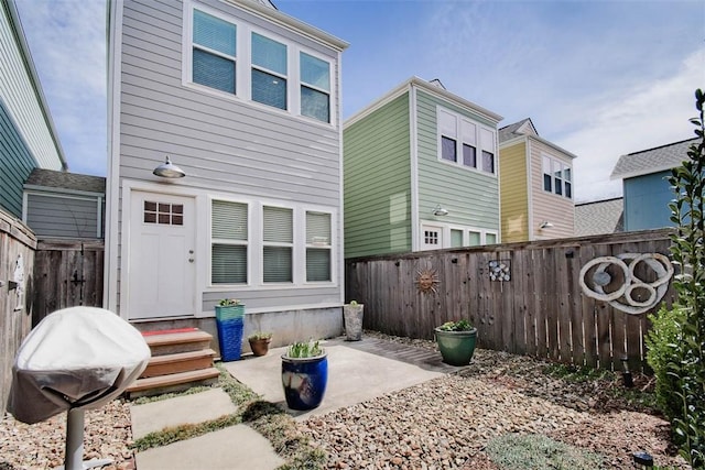 back of house with a fenced backyard and a patio