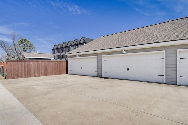 garage featuring concrete driveway and fence