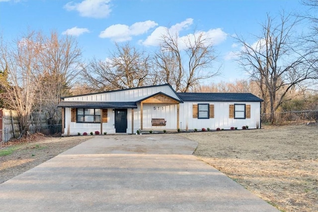 modern inspired farmhouse featuring concrete driveway, fence, and board and batten siding