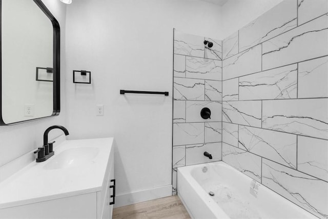 bathroom with washtub / shower combination, vanity, baseboards, and wood finished floors