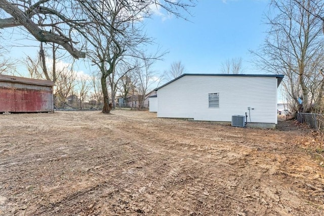 view of yard featuring an outbuilding, central AC, and fence