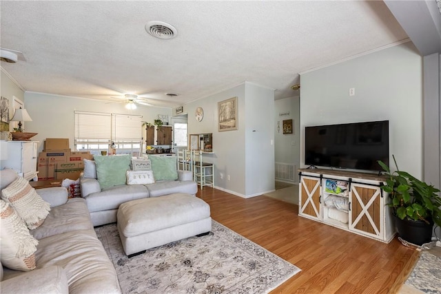 living area featuring visible vents, a textured ceiling, a ceiling fan, and wood finished floors