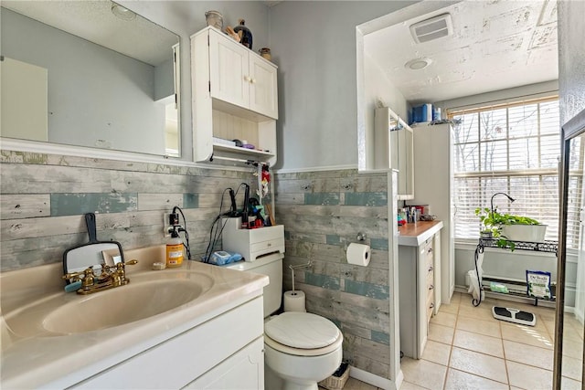 bathroom featuring tile patterned flooring, a wainscoted wall, wood walls, toilet, and vanity