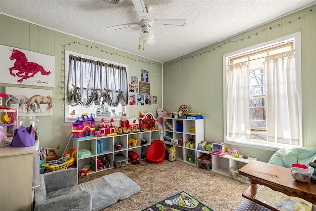 recreation room with carpet flooring, a textured ceiling, and ceiling fan