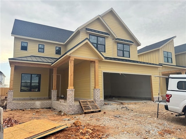 craftsman-style home featuring metal roof, a porch, an attached garage, and a standing seam roof