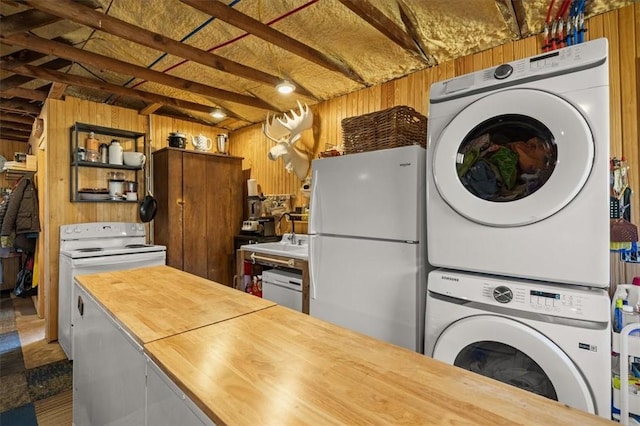 kitchen with stacked washer / dryer, wooden counters, beamed ceiling, wood walls, and white appliances