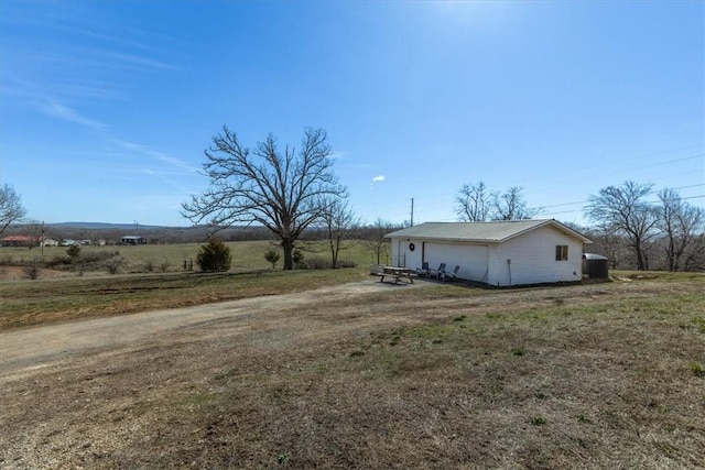 view of yard with a rural view, a garage, an outdoor structure, and dirt driveway