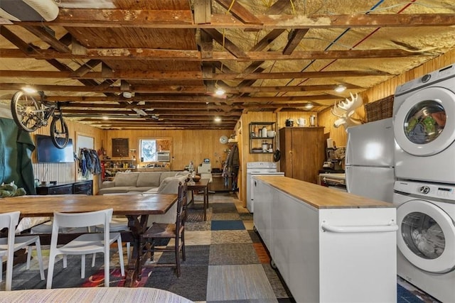 laundry area with laundry area, wood walls, and stacked washer / drying machine