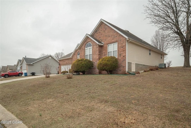 view of front facade featuring cooling unit, brick siding, a garage, and a front yard