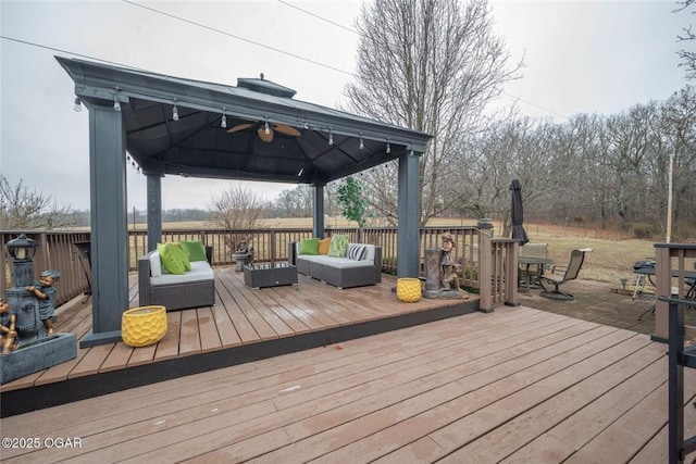 wooden deck featuring a gazebo, an outdoor hangout area, outdoor dining space, and a ceiling fan