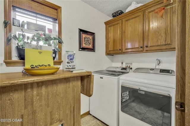 laundry room featuring cabinet space, a textured ceiling, and washing machine and clothes dryer