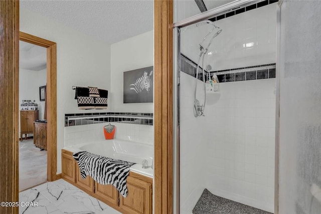 full bath featuring a bath, marble finish floor, a tile shower, and a textured ceiling