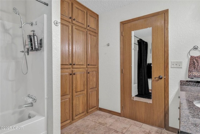 full bath with vanity, baseboards, bathtub / shower combination, tile patterned flooring, and a textured ceiling