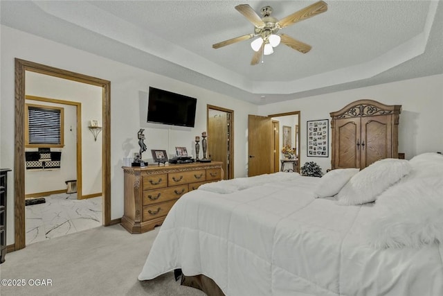 bedroom with a tray ceiling, light carpet, a textured ceiling, and baseboards