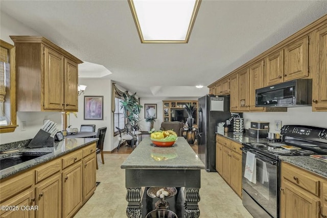 kitchen with dark stone counters, brown cabinets, black appliances, and a center island