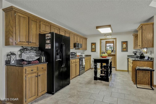 kitchen with brown cabinets, a textured ceiling, black appliances, and baseboards