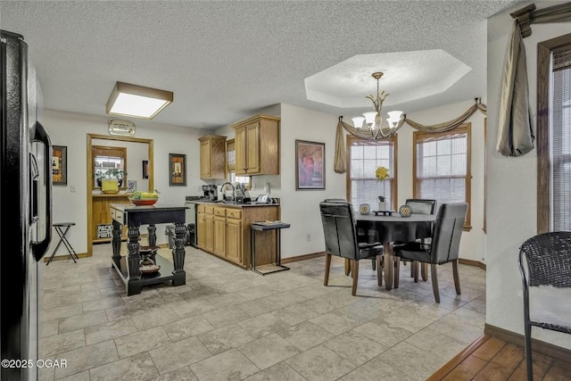 kitchen with a notable chandelier, black fridge, a tray ceiling, a textured ceiling, and a center island