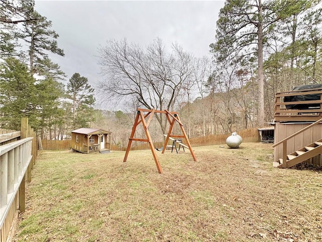 view of yard featuring an outbuilding, a playground, and a fenced backyard