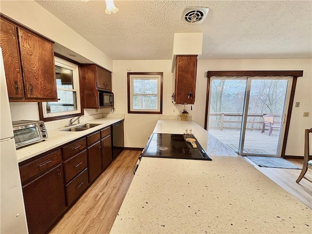 kitchen featuring visible vents, black appliances, light countertops, and a sink