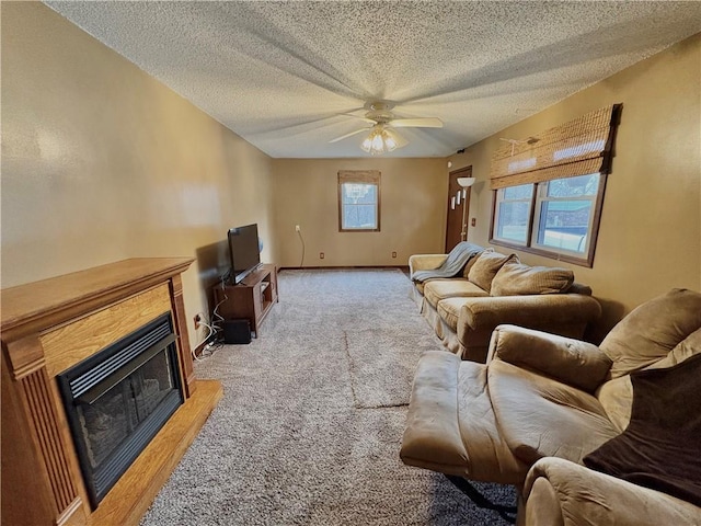 living room with a textured ceiling, a ceiling fan, baseboards, a fireplace, and light carpet