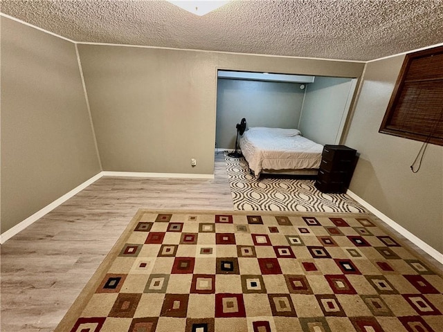 unfurnished bedroom with wood finished floors, baseboards, and a textured ceiling