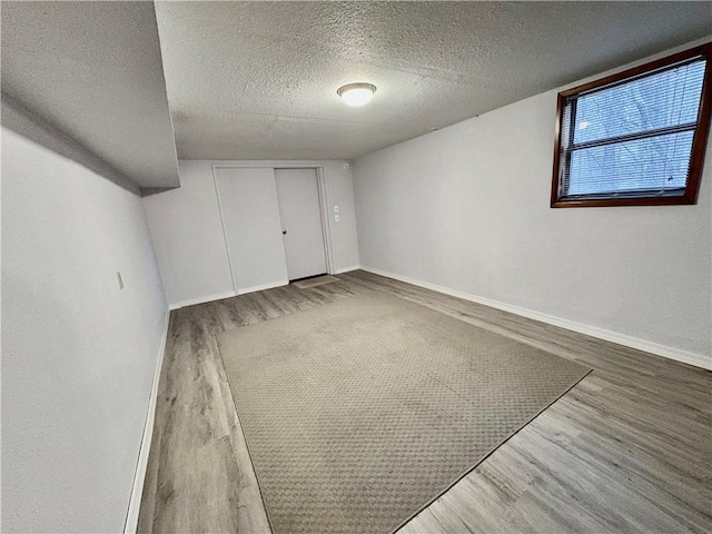 interior space featuring baseboards, a textured ceiling, and wood finished floors