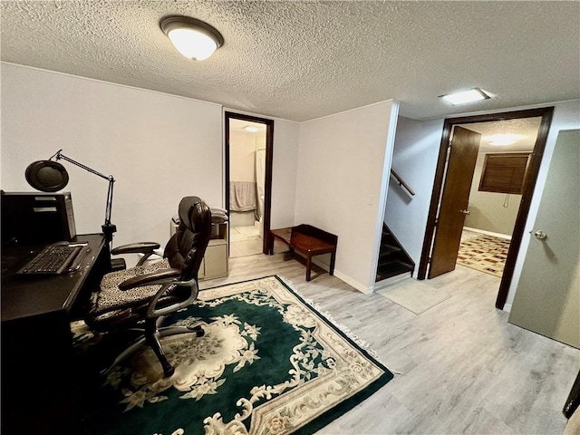 office featuring light wood-style flooring, a textured ceiling, and baseboards