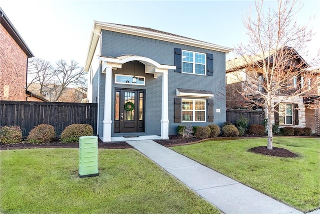 view of front facade featuring a front yard, fence, and brick siding