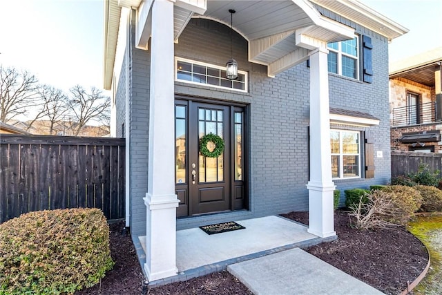 property entrance with french doors, brick siding, and fence