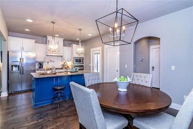 dining room with dark wood-type flooring, baseboards, recessed lighting, arched walkways, and a notable chandelier