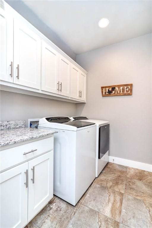 washroom featuring baseboards, cabinet space, and separate washer and dryer