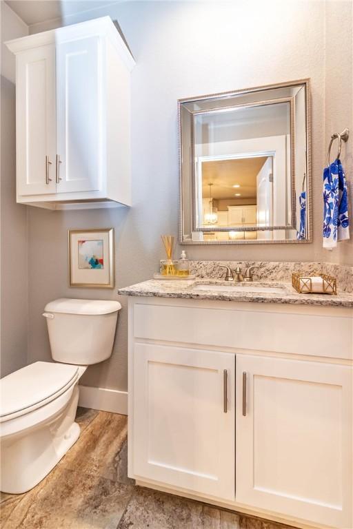 half bathroom featuring toilet, vanity, and baseboards