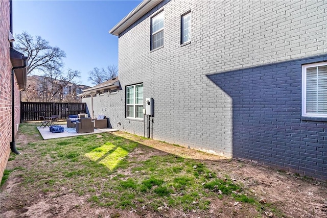 exterior space featuring fence, a patio area, and brick siding