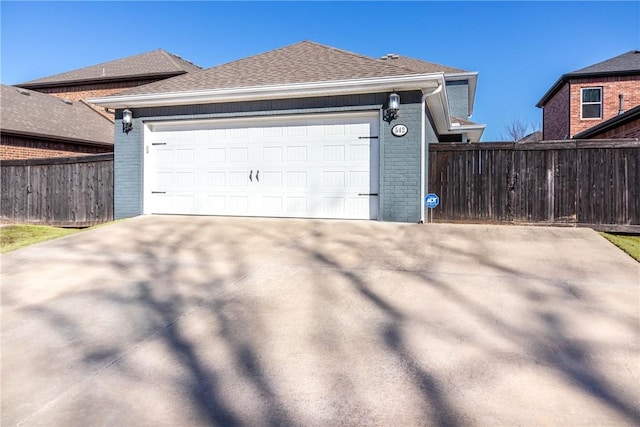 view of property exterior with fence, driveway, roof with shingles, a garage, and brick siding