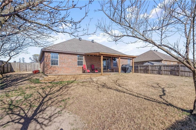 rear view of house with a patio, a fenced backyard, brick siding, and roof with shingles