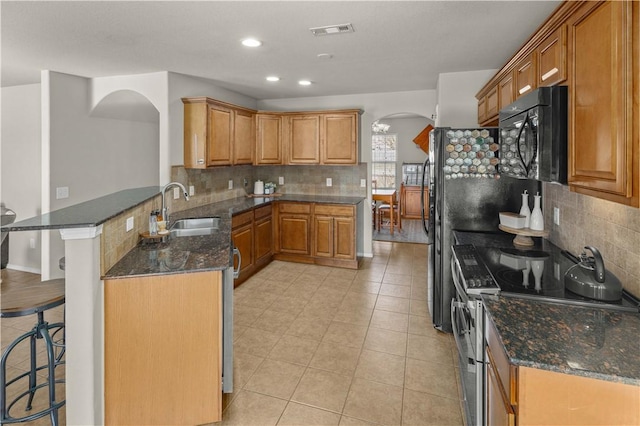 kitchen with visible vents, range with two ovens, arched walkways, a sink, and black microwave