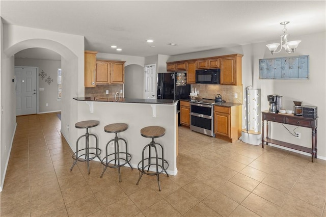 kitchen with light tile patterned floors, a kitchen breakfast bar, arched walkways, and black appliances