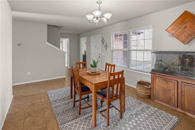 tiled dining room featuring baseboards and a chandelier