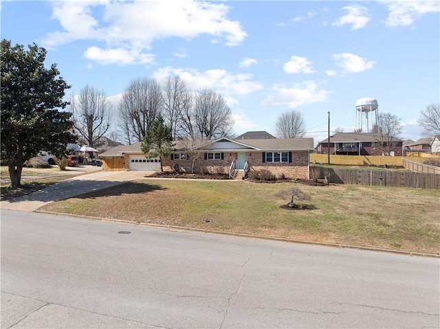 view of front facade featuring a garage, concrete driveway, a front yard, and fence