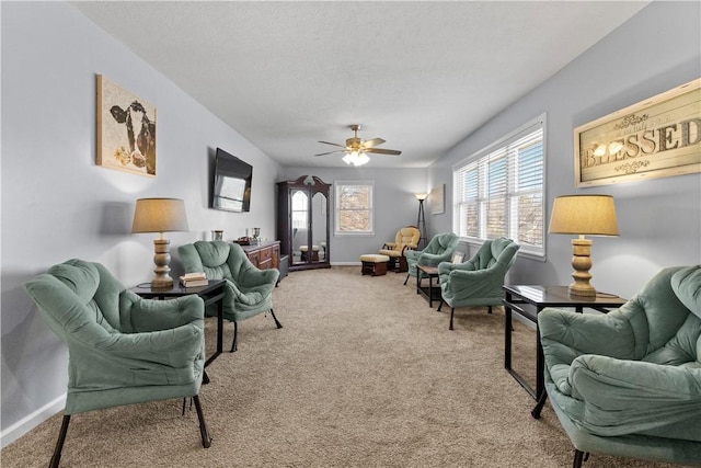 living room with baseboards, a ceiling fan, carpet flooring, and a textured ceiling