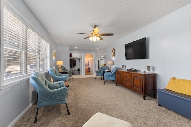 living room featuring baseboards, light colored carpet, and a ceiling fan