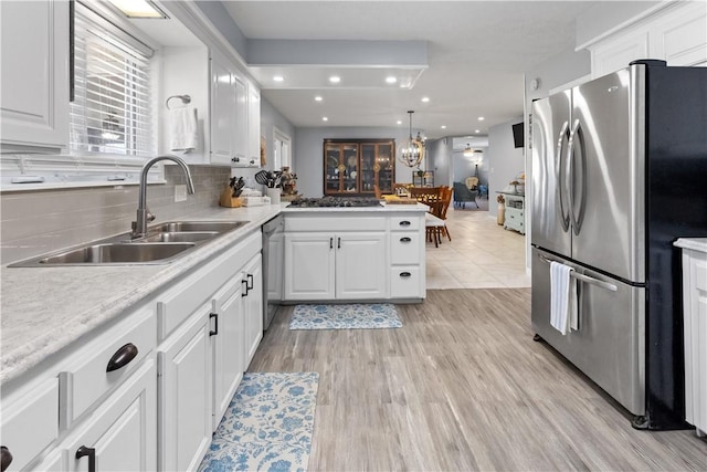 kitchen with a peninsula, a sink, light countertops, white cabinets, and appliances with stainless steel finishes