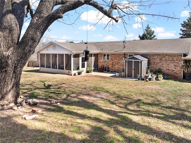 back of house with brick siding, a lawn, a storage shed, an outdoor structure, and a sunroom