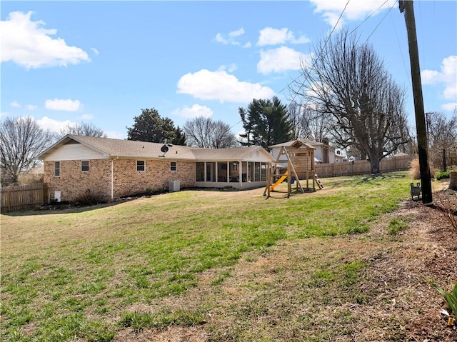 rear view of property with a fenced backyard, brick siding, a yard, and a sunroom